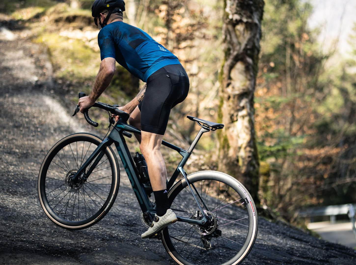 Ein ERennrad Fahrer bewältigt eine ansteigende Straße mit seiner BMC Roadmachine AMP mit Mahle Hinterradmotor